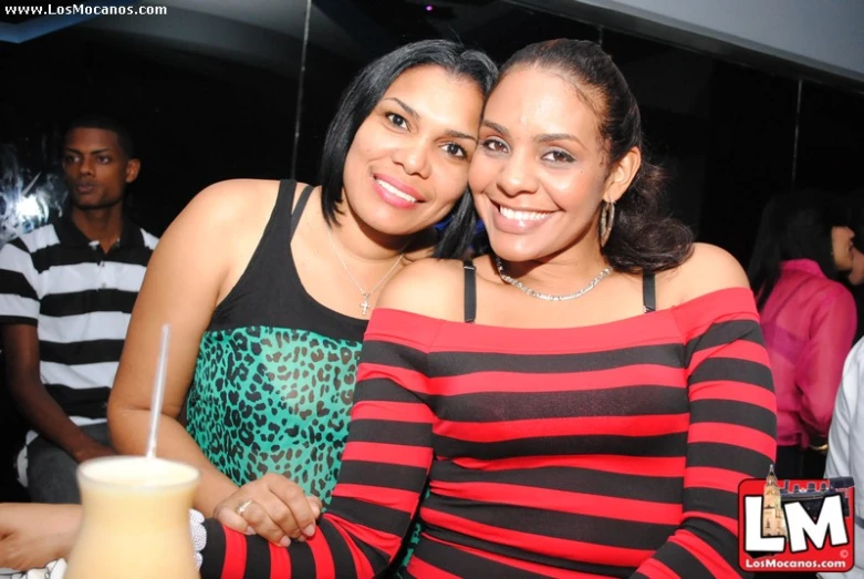 two beautiful young ladies posing in front of a drink