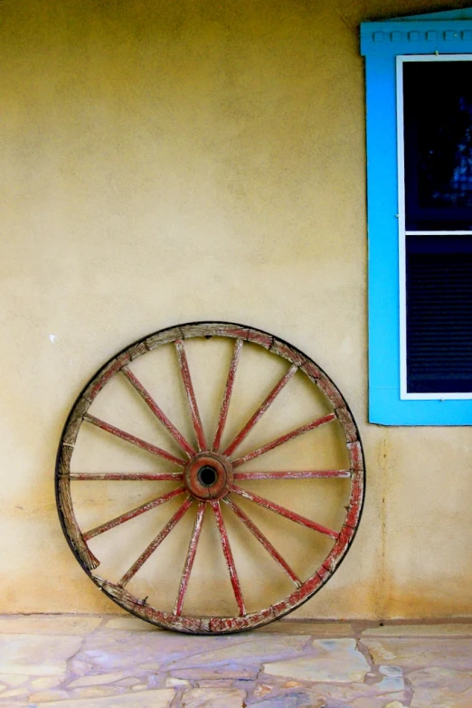 an old, rusty metal wheel hanging on a wall in front of a window