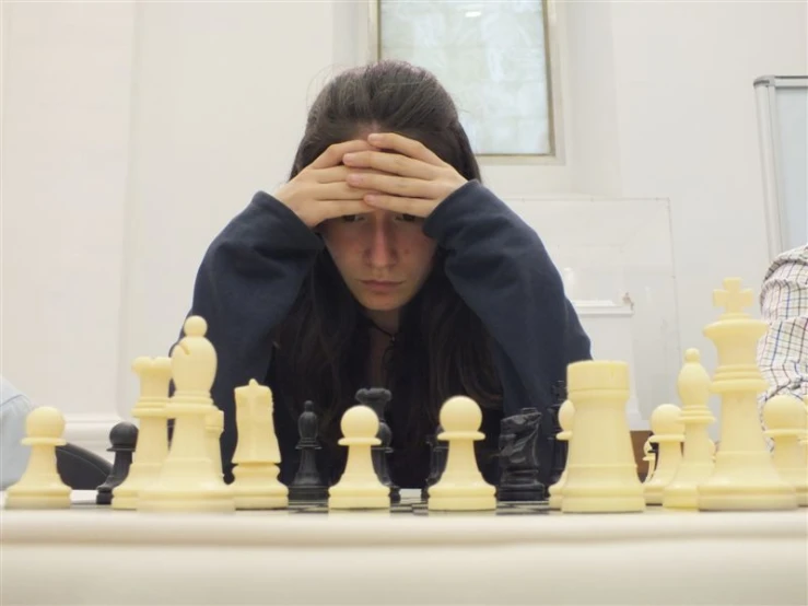 a woman who is kneeling behind the chess board