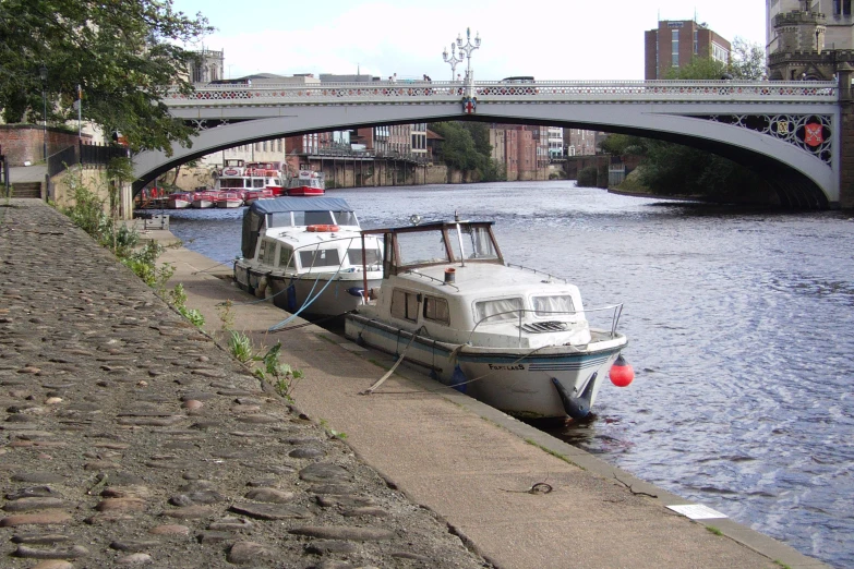 a boat tied to a pier next to a bridge over the water