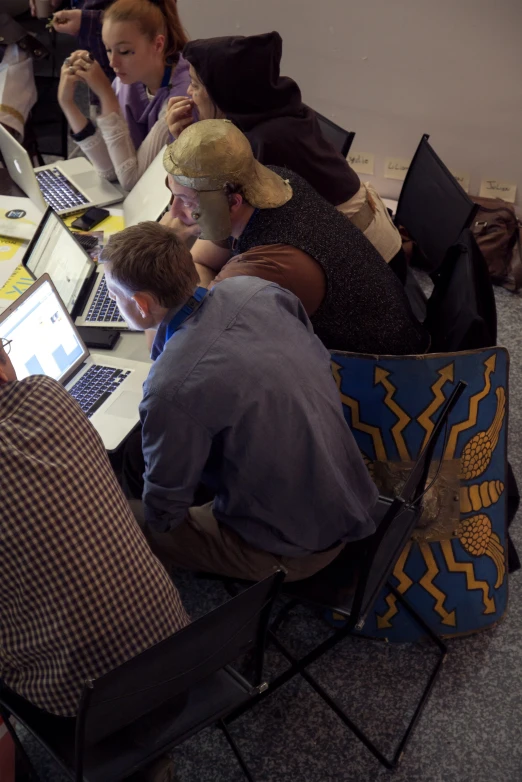 a group of people are sitting at a table with laptops