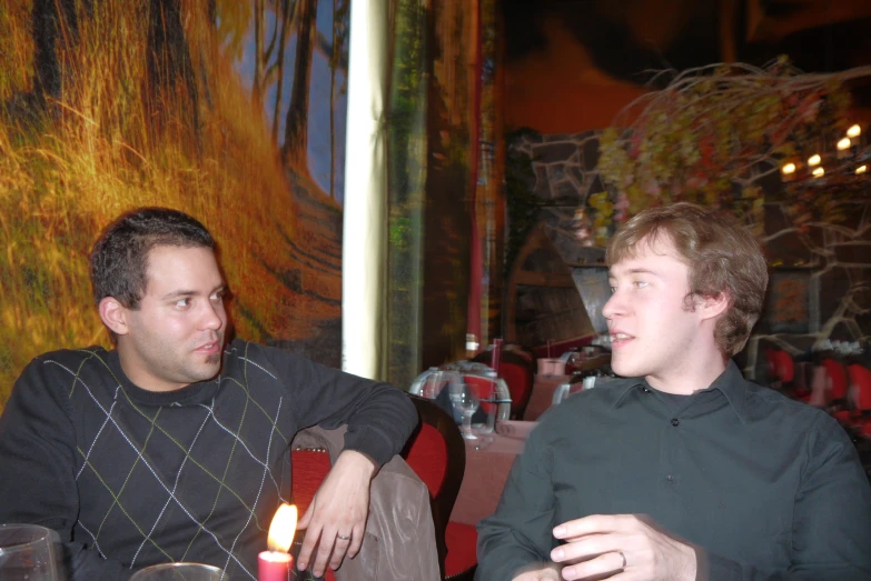 two men are sitting around eating at a restaurant