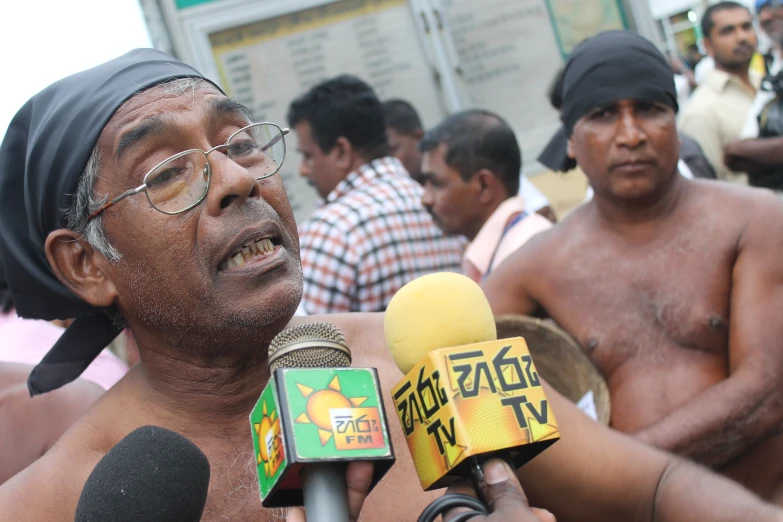 a man with glasses on speaking to media