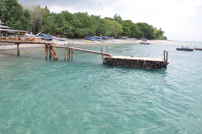 a dock extending into the water with many boats parked in the water behind it