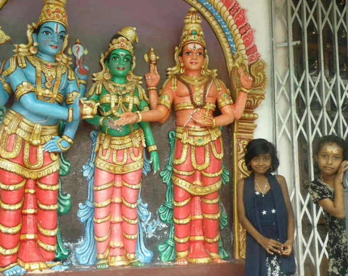 three ladies are standing in front of statues