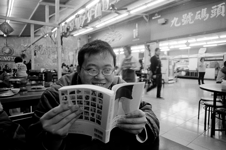 a man reading a book in a cafeteria