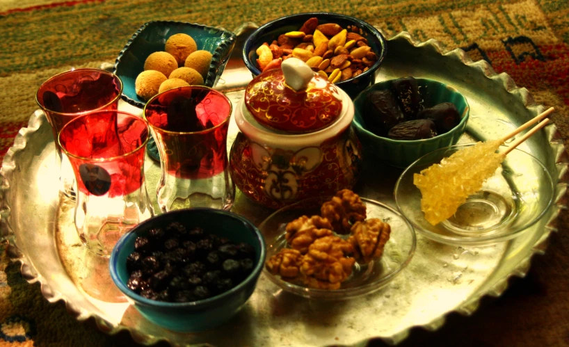 a silver tray with nuts, jams and drinks on it