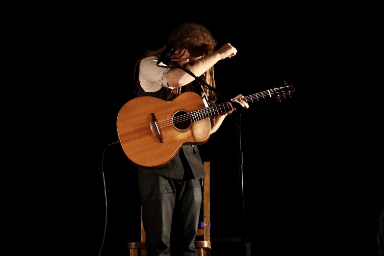 a man on stage with a guitar and microphone