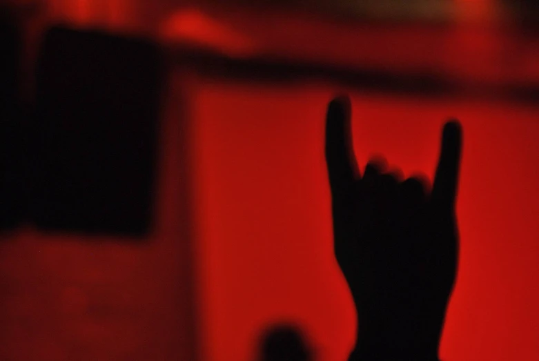 a black silhouette of the person on stage with their hand up