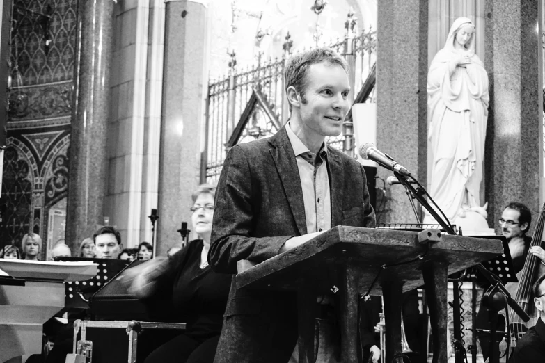 man standing at a microphone speaking into a microphone