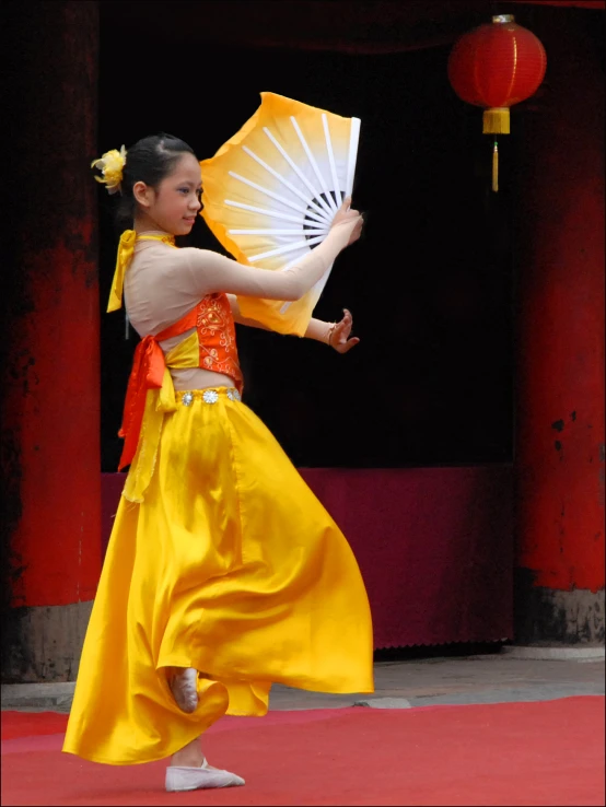 a young child in chinese style clothing and holding up an umbrella