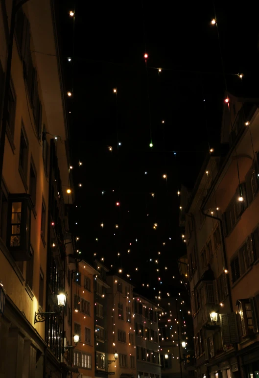 the night view of a very long row of houses and buildings with many lights hanging in the air