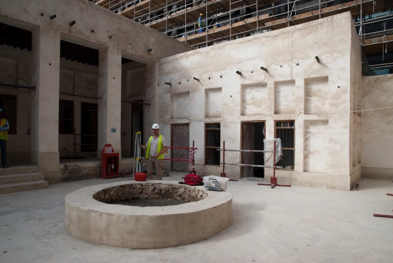 two men in safety gear standing inside an unfinished building