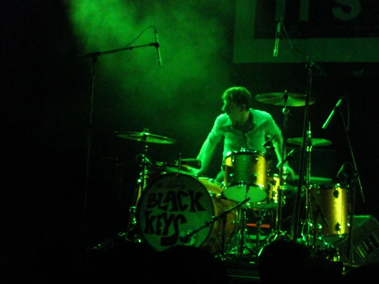 a man is playing drums in front of green light