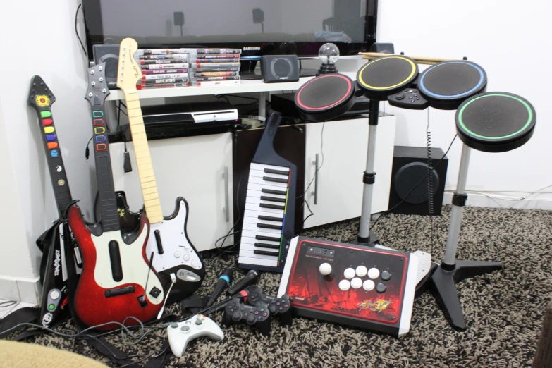 musical equipment including a guitar, amp, piano and keyboard are neatly placed on the floor in front of a tv