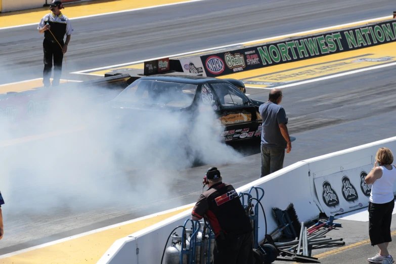 a black car is smoking and some people