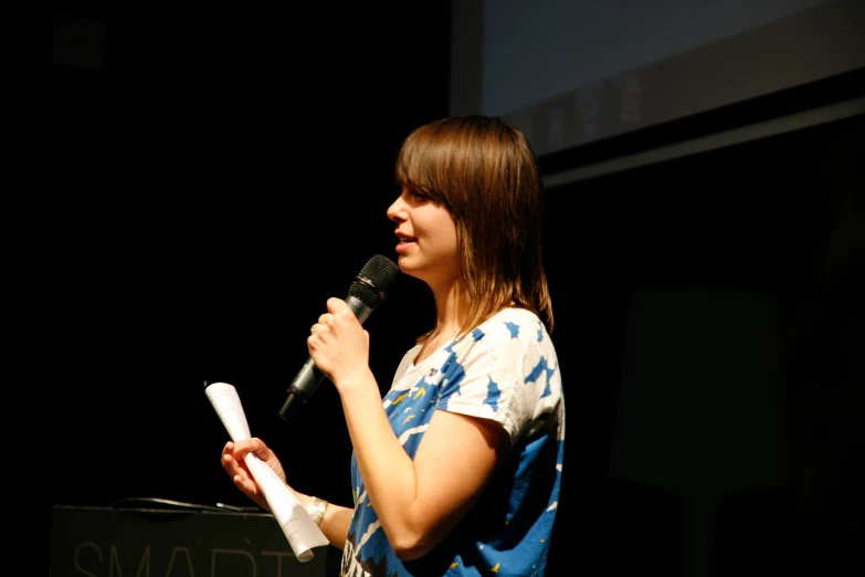 a woman standing at a microphone and talking into the microphone