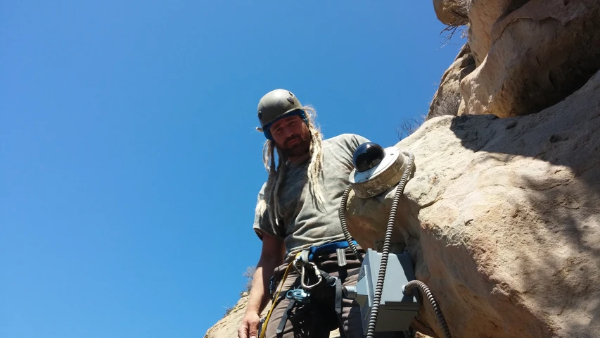 a man with helmet on standing in front of a rock