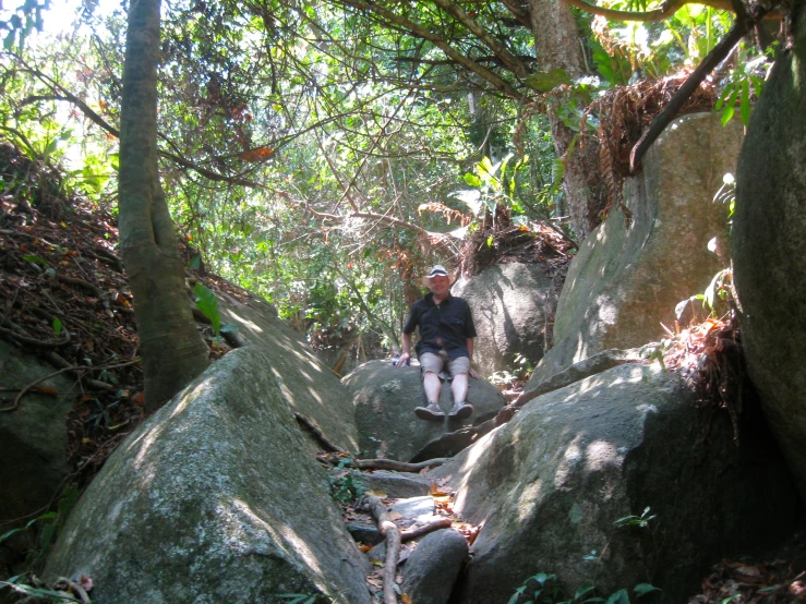 a person walking between large rocks on a path in a forest