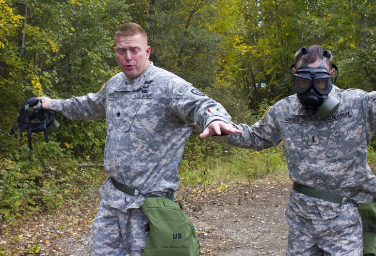 two people in camouflage uniforms hold hands as they stand on a path in the woods