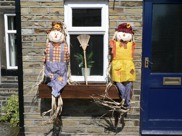 two scarecrows sitting in front of a house