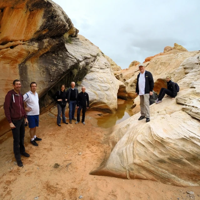 group of young people standing in front of a rock formation