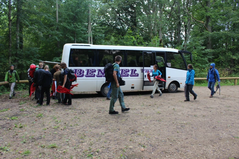 a group of people are standing in front of a bus