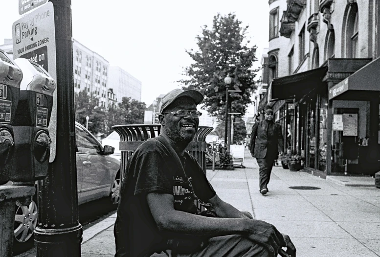 a man is sitting on a parking meter in front of a street