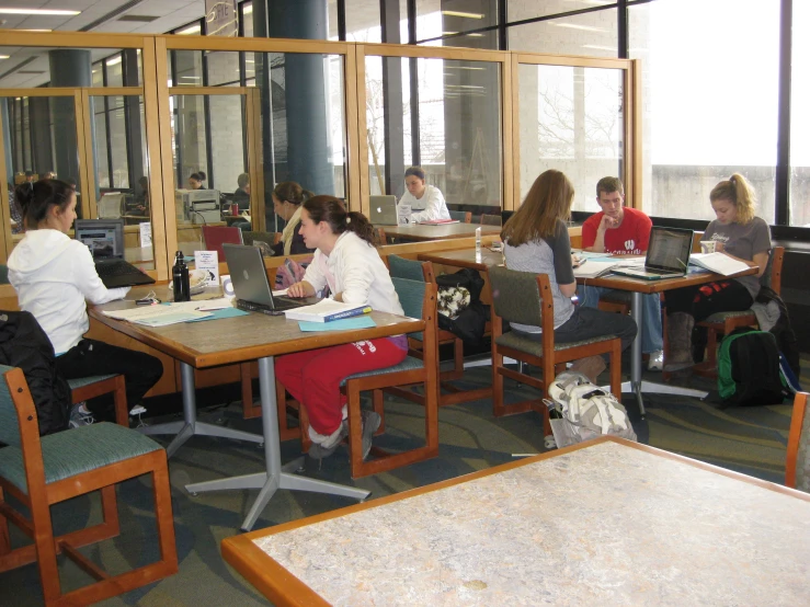 several students studying in a classroom with a glass window