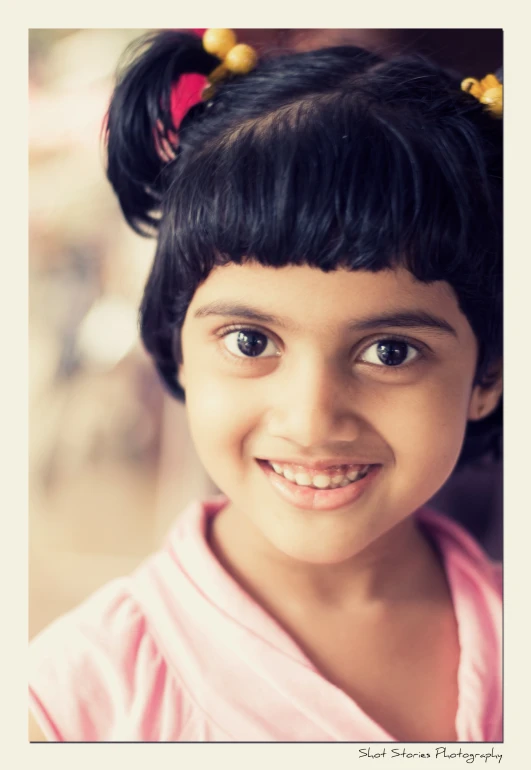 a little girl with her black hair in a bun smiling