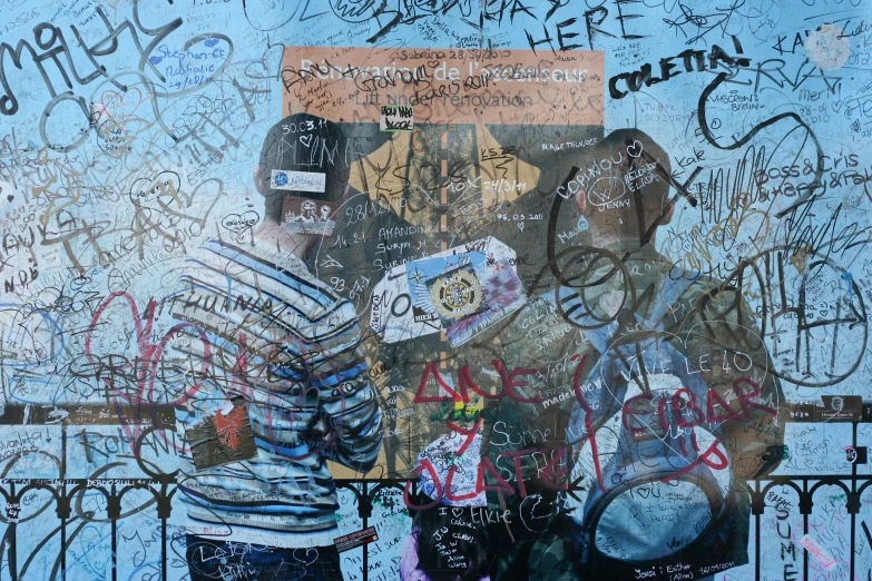 two people stand near a wall covered in graffiti