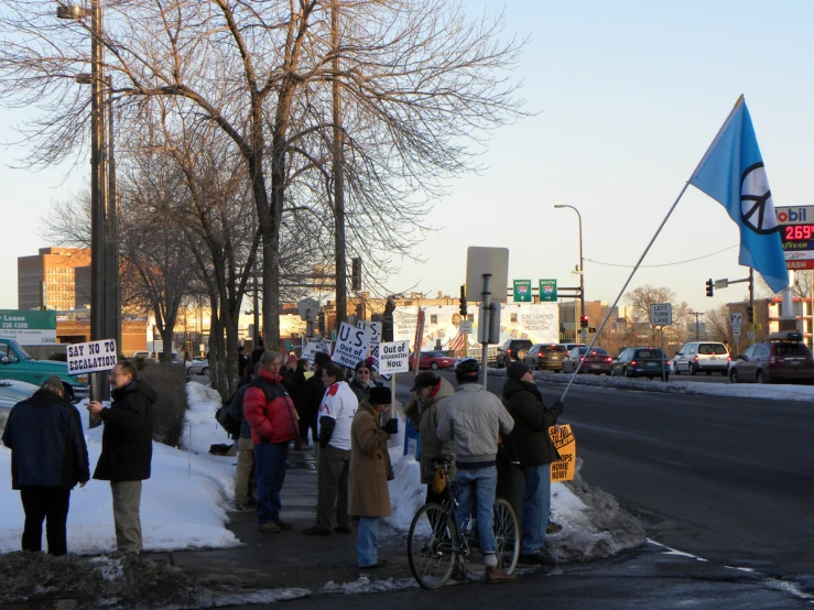 people on the side walk next to the street holding signs