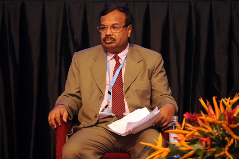 a man is sitting down in front of a black background