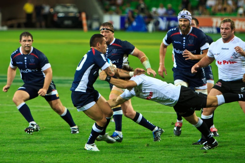 the rugby players on the field are trying to break the tackler