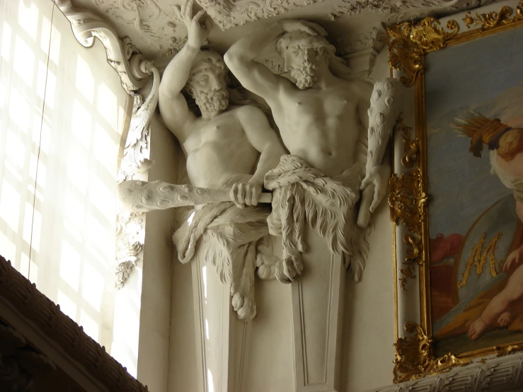 sculpture of two  men with a gold frame around the wall