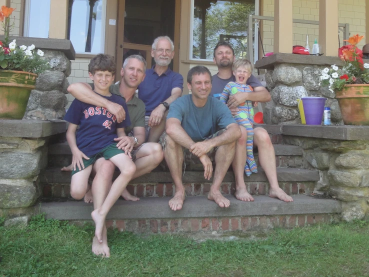 three adults and two s posing for picture on steps