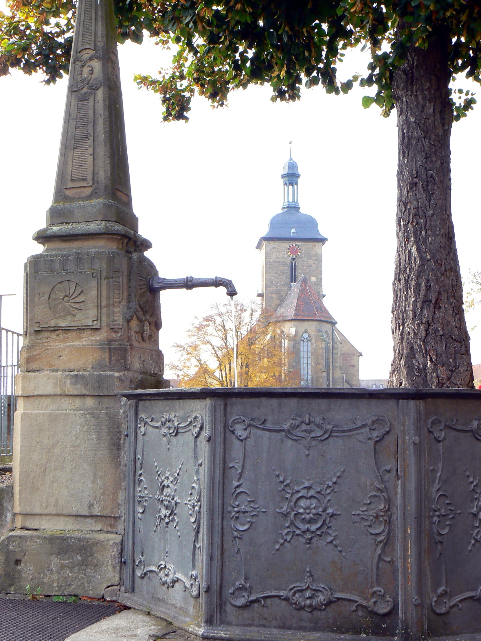 a clock tower is in the distance near a concrete fence