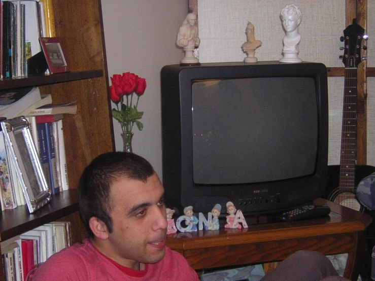 a man in pink is sitting in front of a television