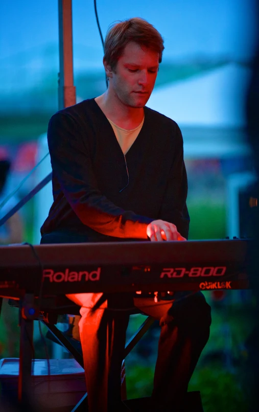 a man with blonde hair sitting in front of a keyboard
