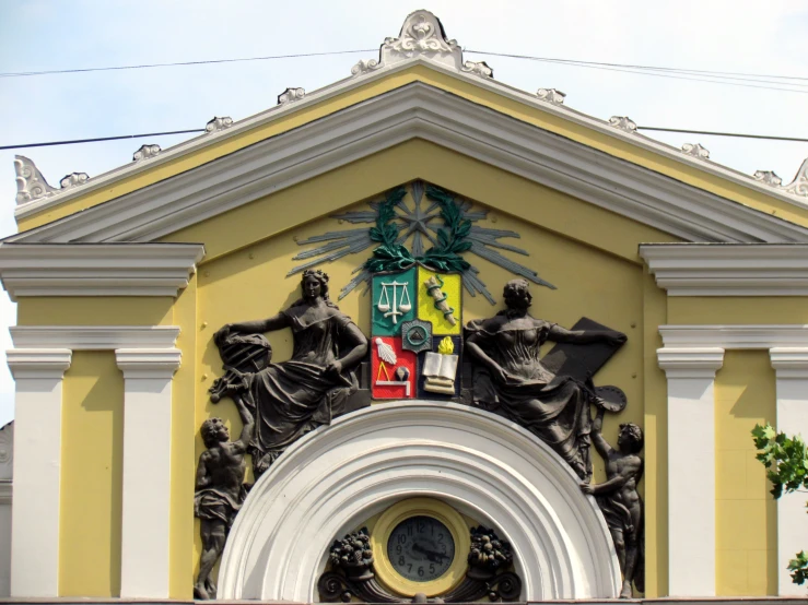 an ornate clock above a doorway, with statues in front of it