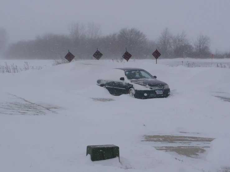 a car parked in the snow next to an orange traffic sign