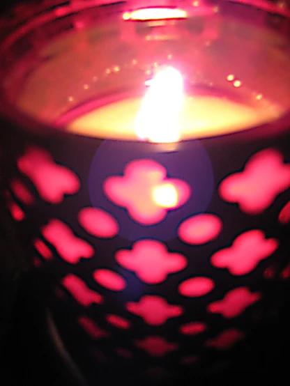 a lit candle with a black background and a pink hearts design