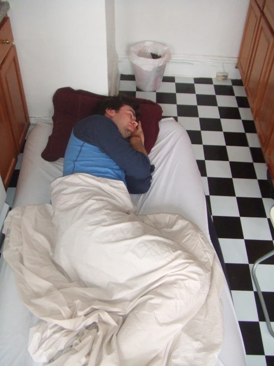 a man laying in bed next to a black and white checkered floor