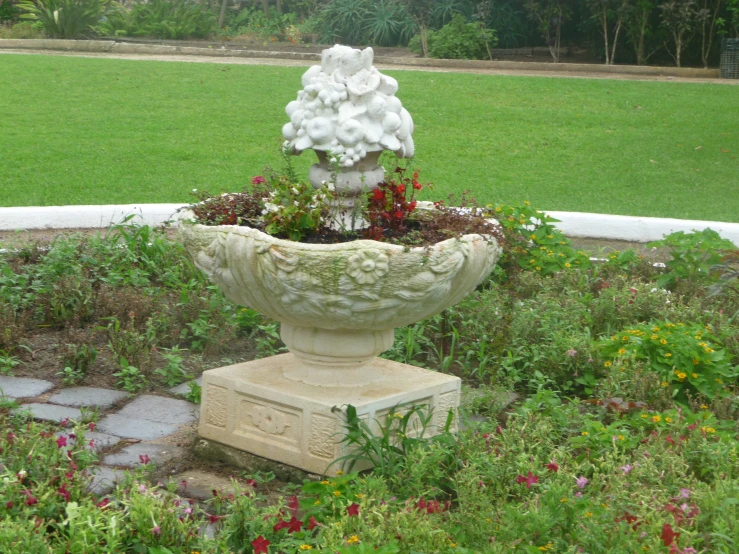 a very pretty white fountain in a yard