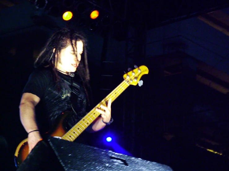 a musician with dreadlocks standing in front of a stage holding a bass