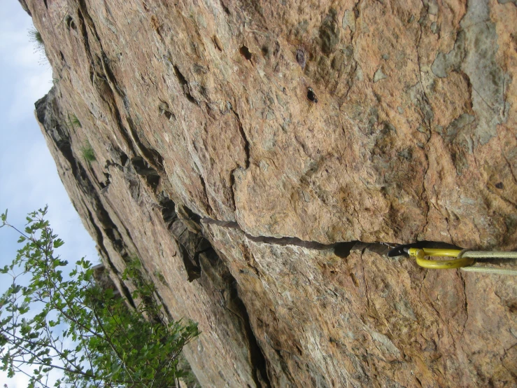 a rock climbing scene with a rope and poles on a narrow ledge