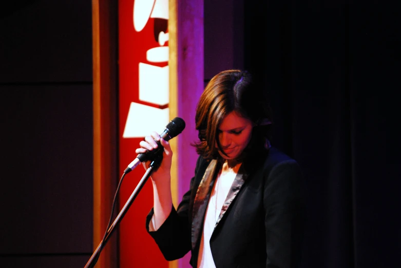 a woman holding a microphone while wearing a suit