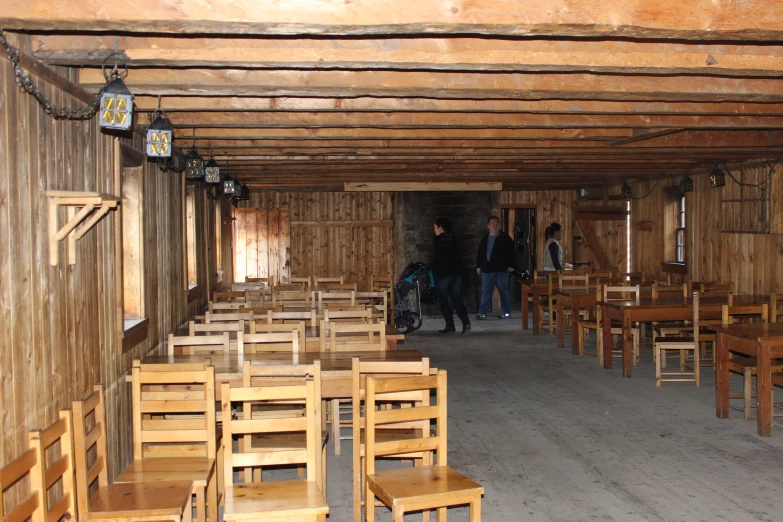 several people stand in an empty room with tables and chairs