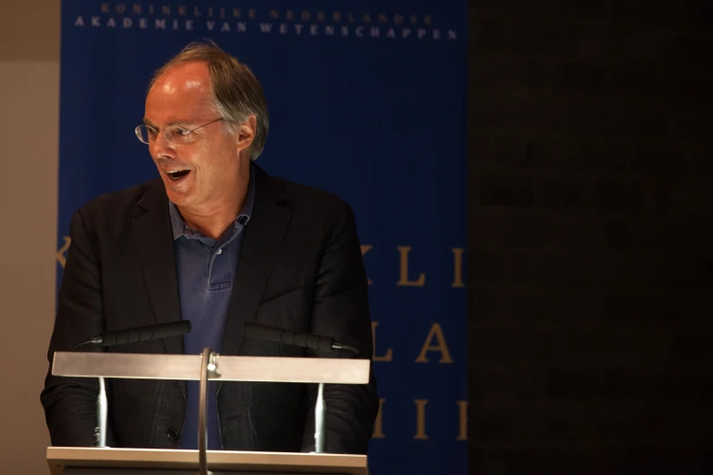 a man in glasses stands behind a podium