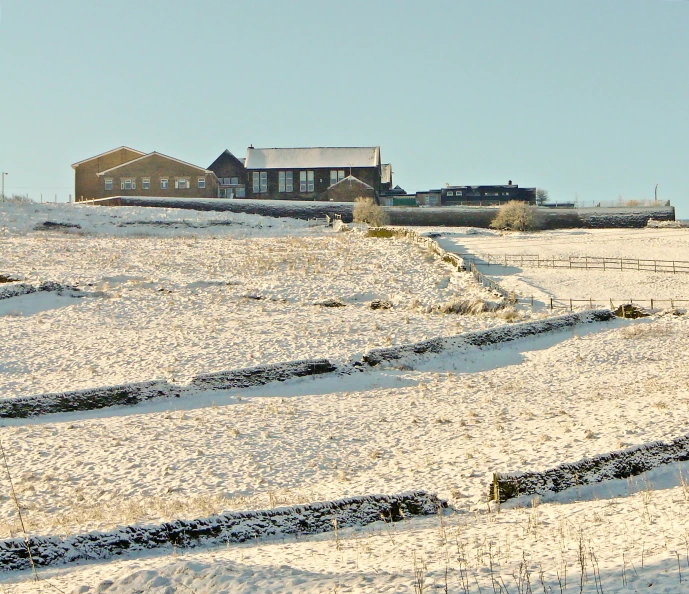 snow covers a field in front of two buildings